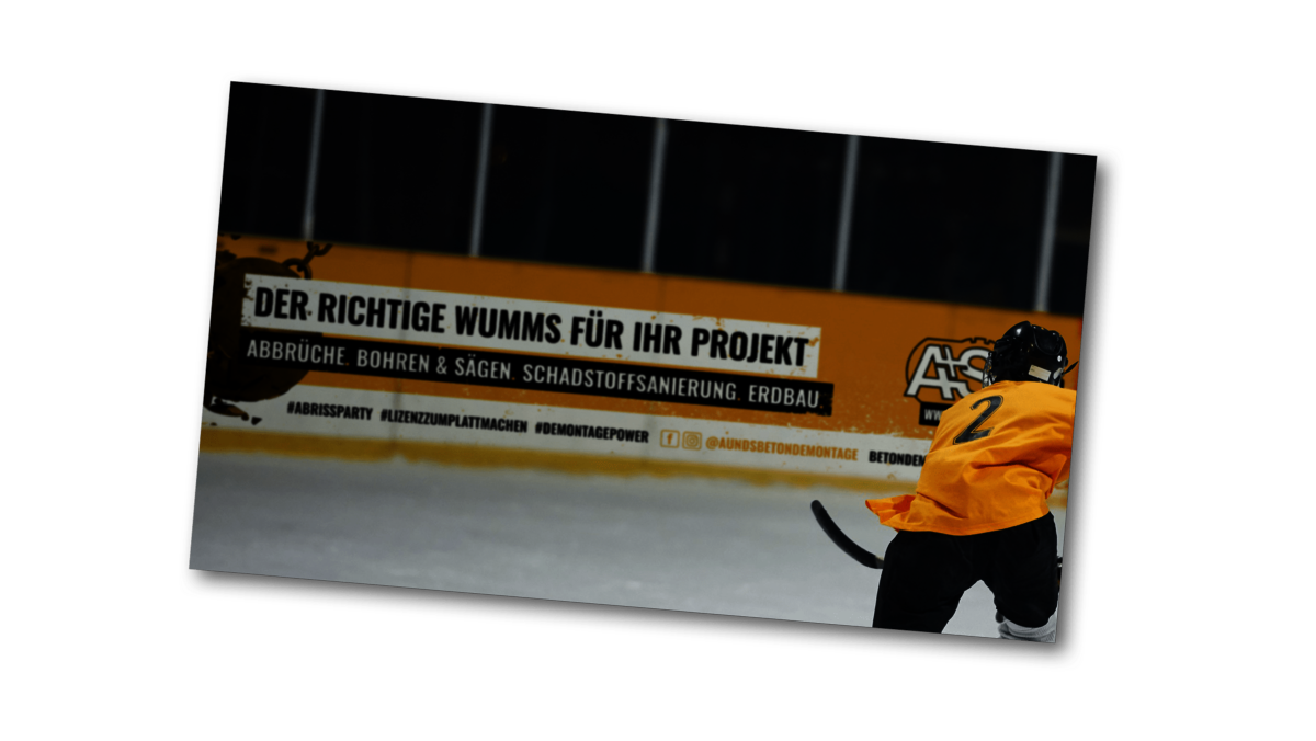 Das Bild zeigt eine Bandenwerbung der A&S Betondemontage GmbH beim Eishockey.